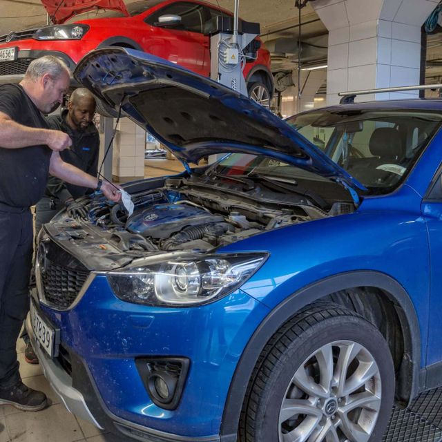 Mekaniker snakker ved panseret til blå Volvo